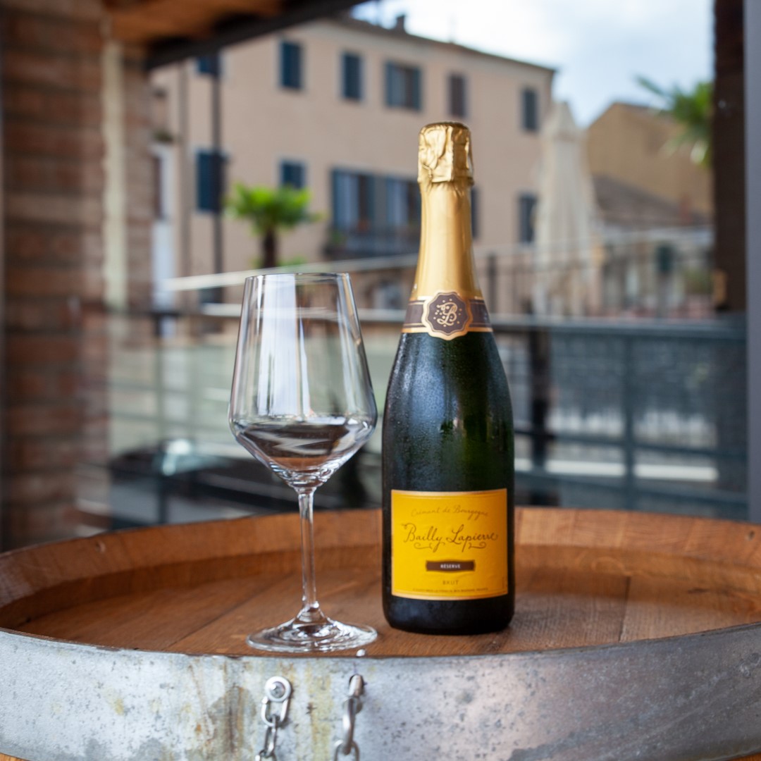 bottiglia di vino e calice sopra una botte all'esterno del bar